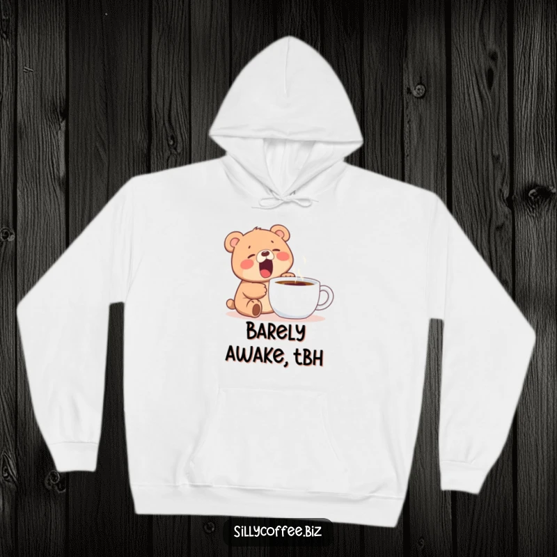 Funny hoodie featuring a kawaii bear cub yawning widely next to a steaming coffee mug, perfect for cozy mornings.