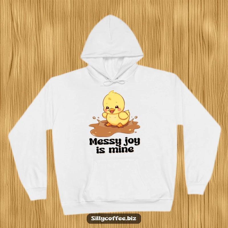 Funny hoodie with a kawaii duckling gleefully splashing in a spilled coffee puddle, radiating warmth and playful energy.